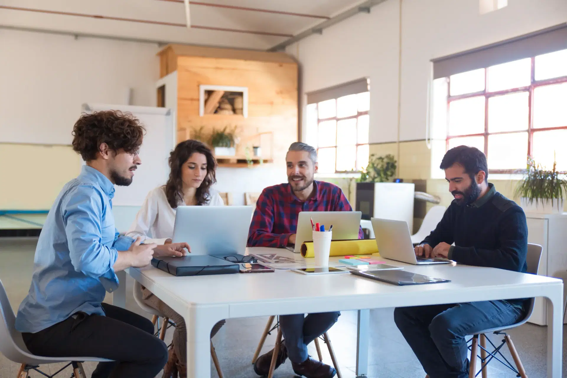 Four people working together at one table with laptops