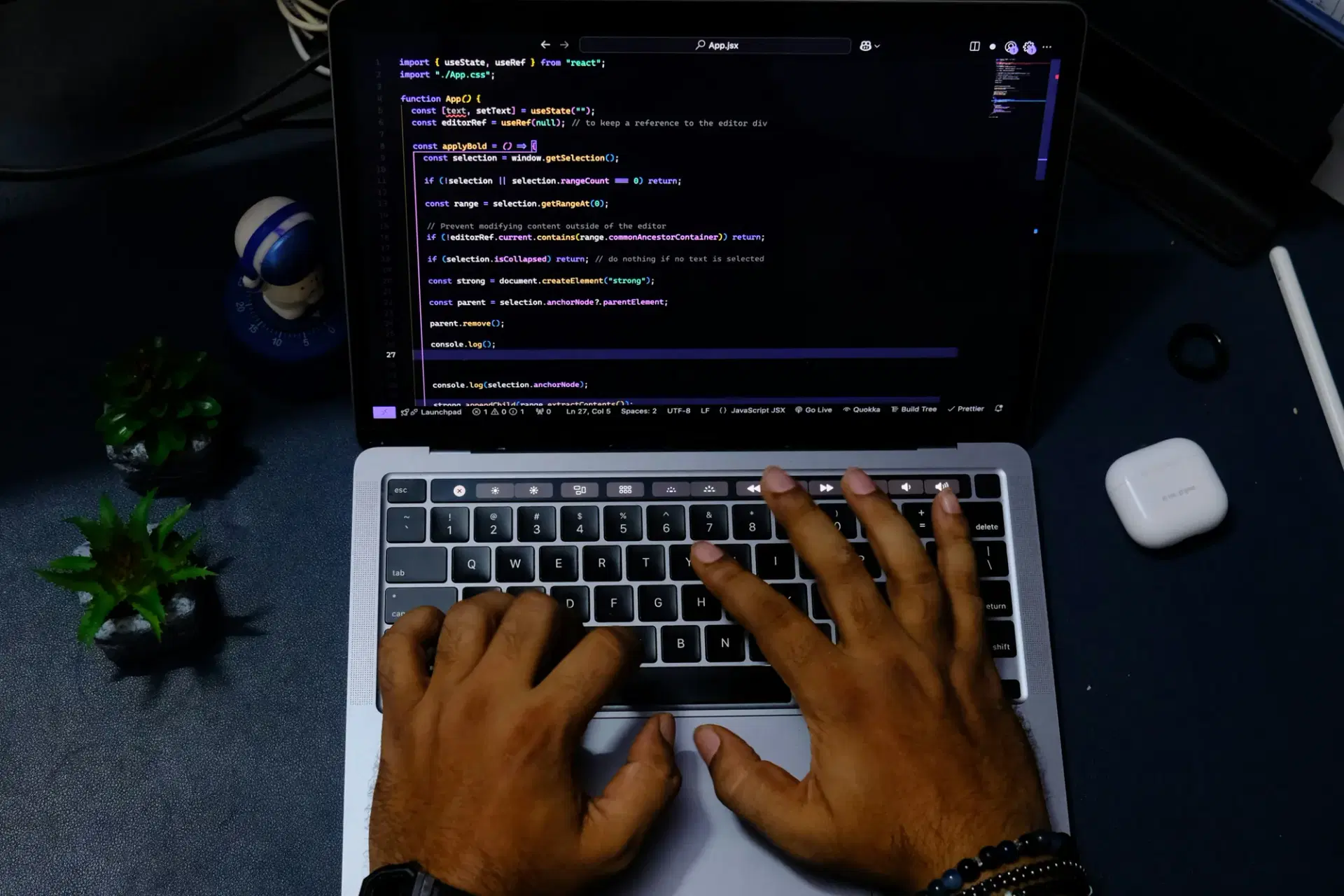 Hands typing on a laptop showing a code editor